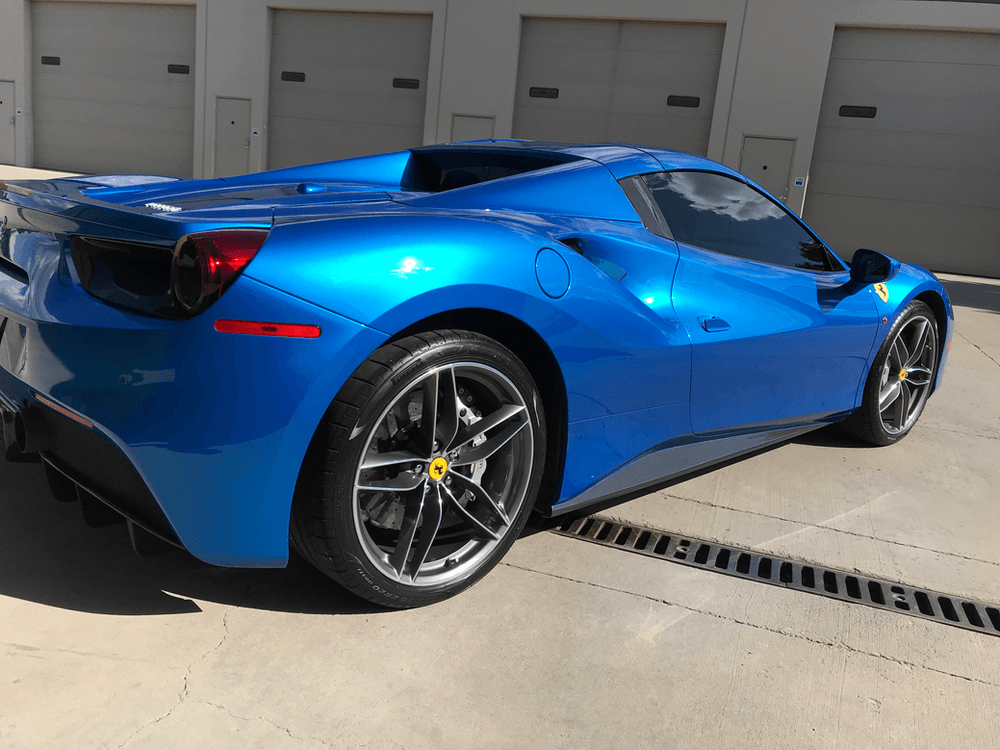 A blue sports car is parked in front of a garage.
