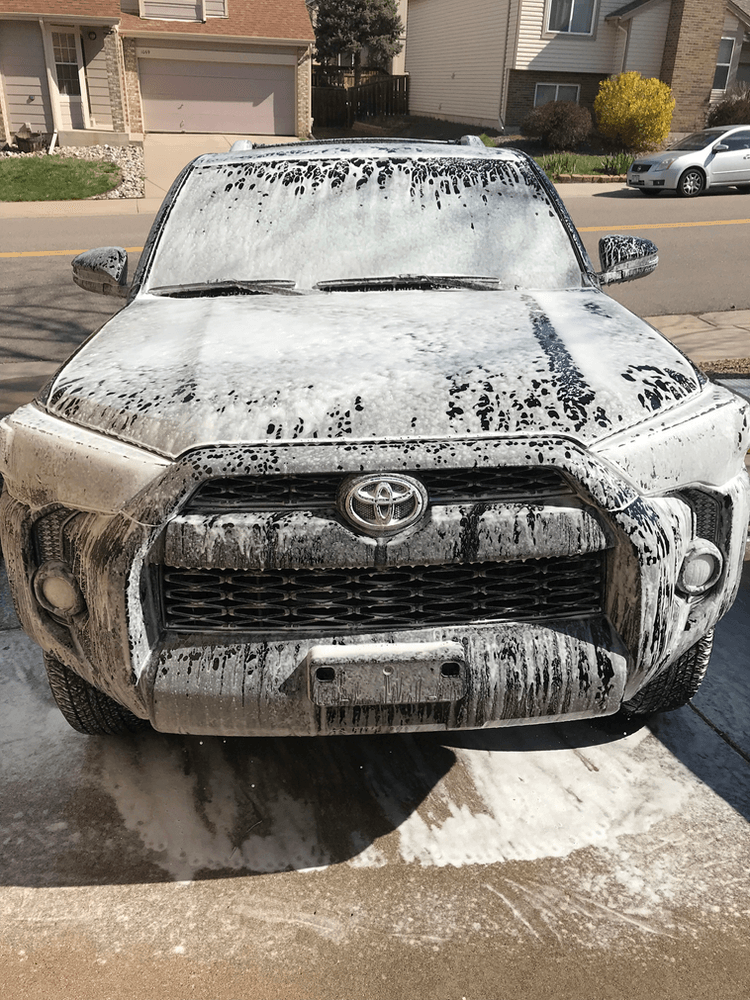 A toyota 4runner is covered in foam and is parked on the side of the road.