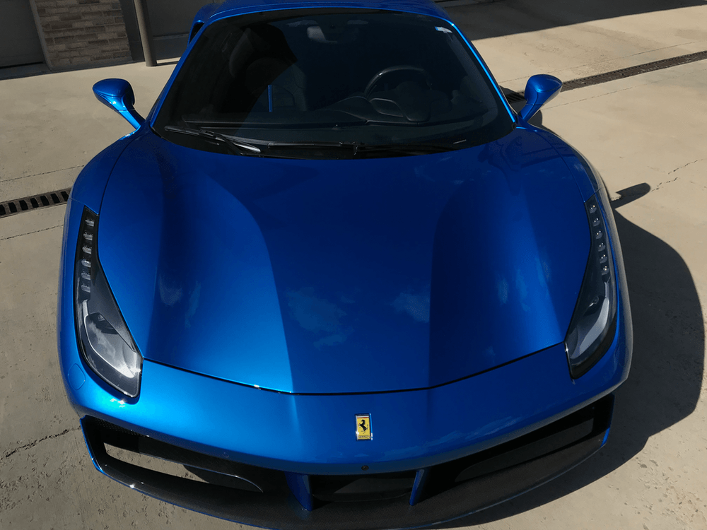 A blue ferrari 488 is parked on the side of the road