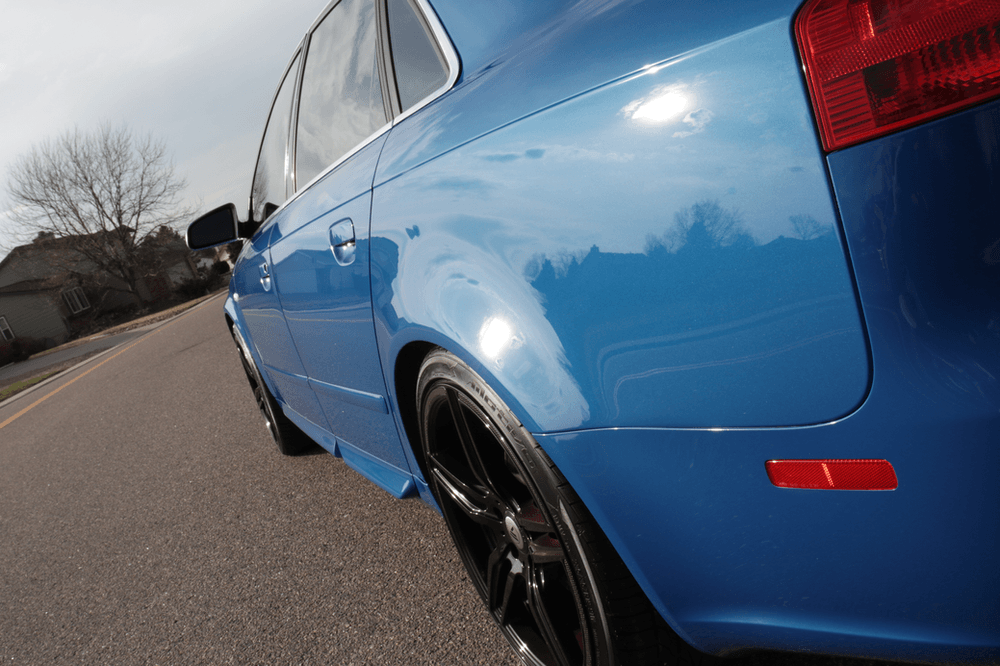 A blue car is parked on the side of the road.