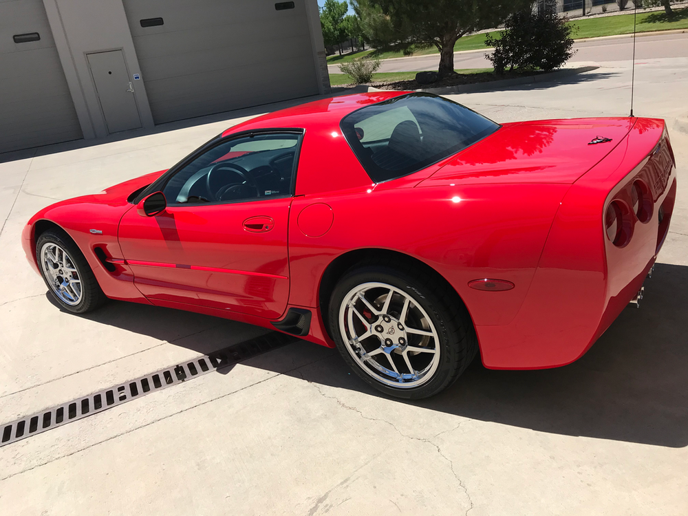 A red corvette is parked in a parking lot.