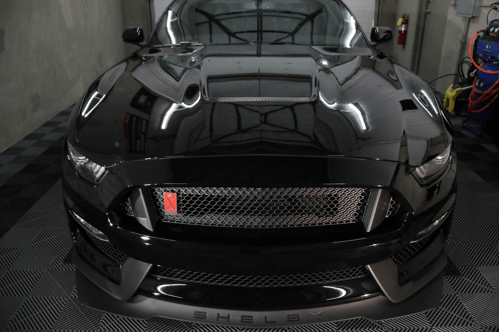 A black ford mustang is parked in a garage.