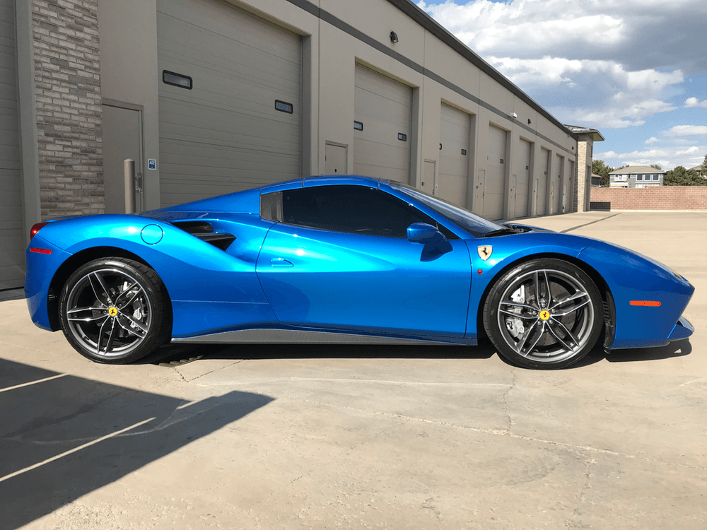 A blue sports car is parked in front of a building.