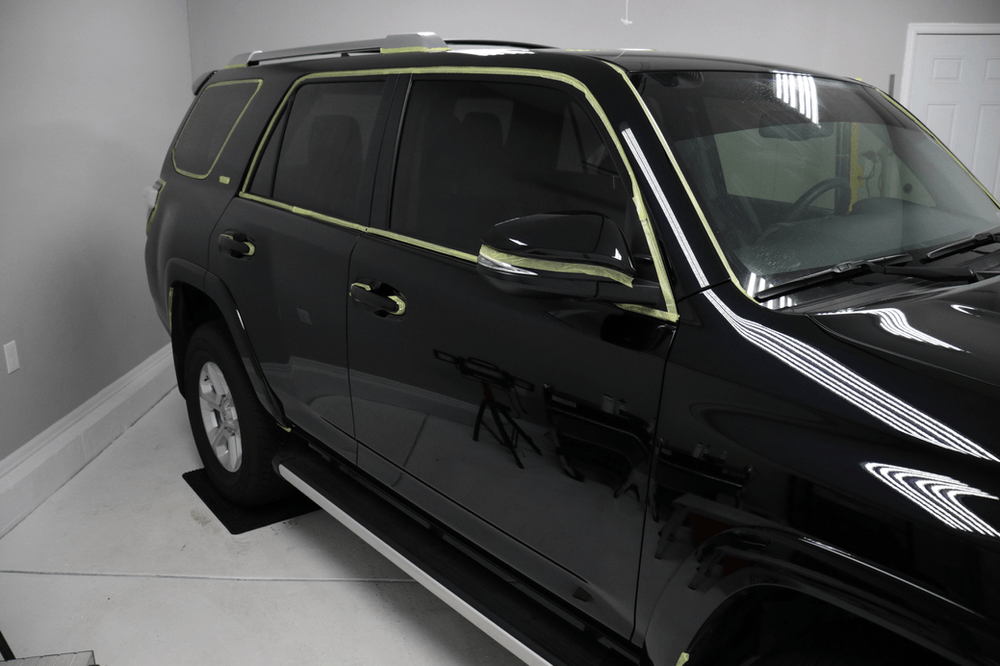A black suv is sitting on a white floor in a garage.