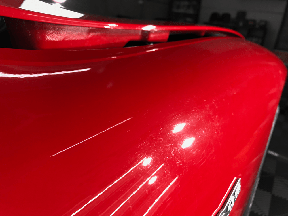 A close up of a red car 's hood in a garage.