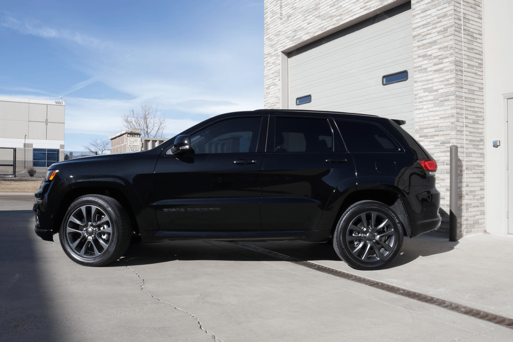 A black jeep grand cherokee is parked in front of a garage door.