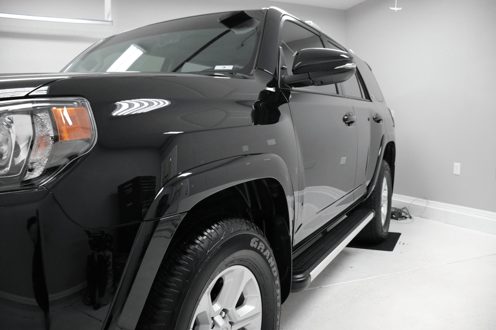 A black toyota 4runner is parked in a garage.