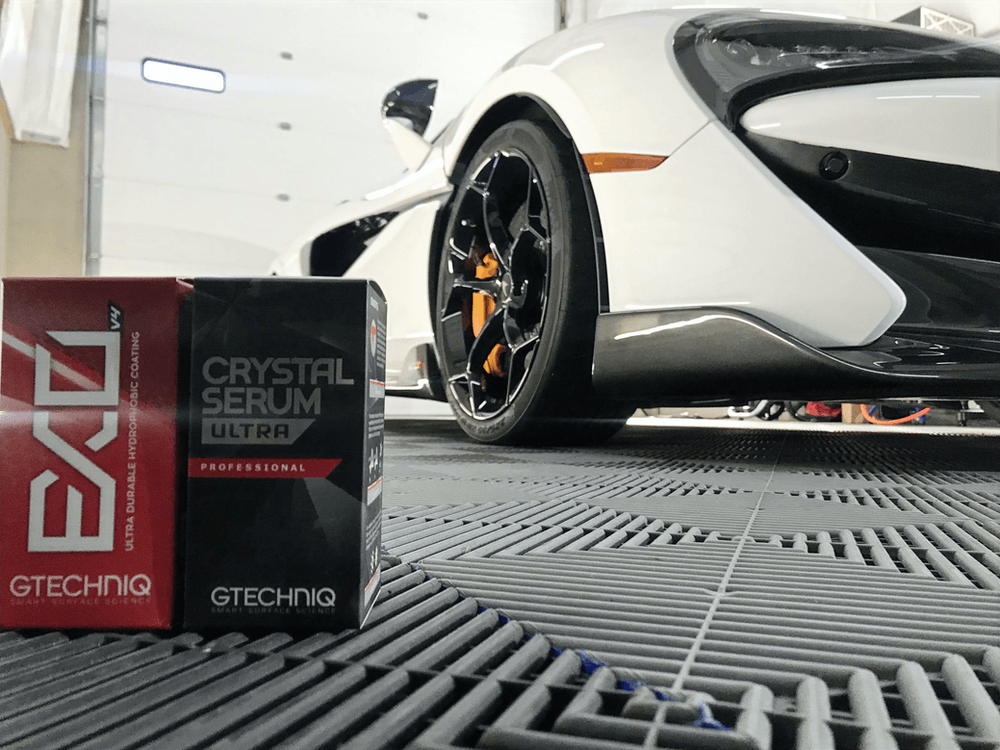 A white car is parked next to a box of crystal serum