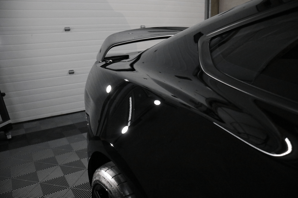 A black car is parked in a garage next to a garage door.