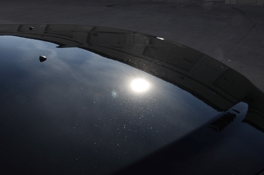 The sun is reflected in the windshield of a black car