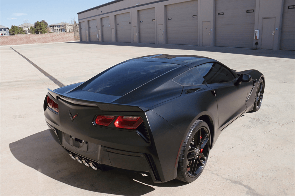 A black sports car is parked in front of a garage.