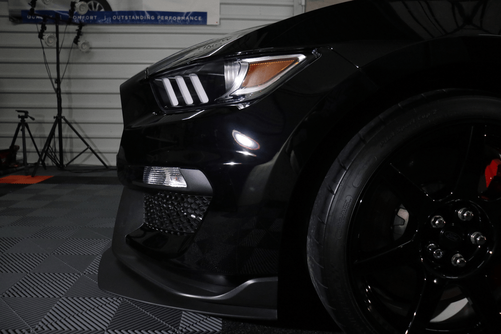 A black ford mustang is parked in a garage.