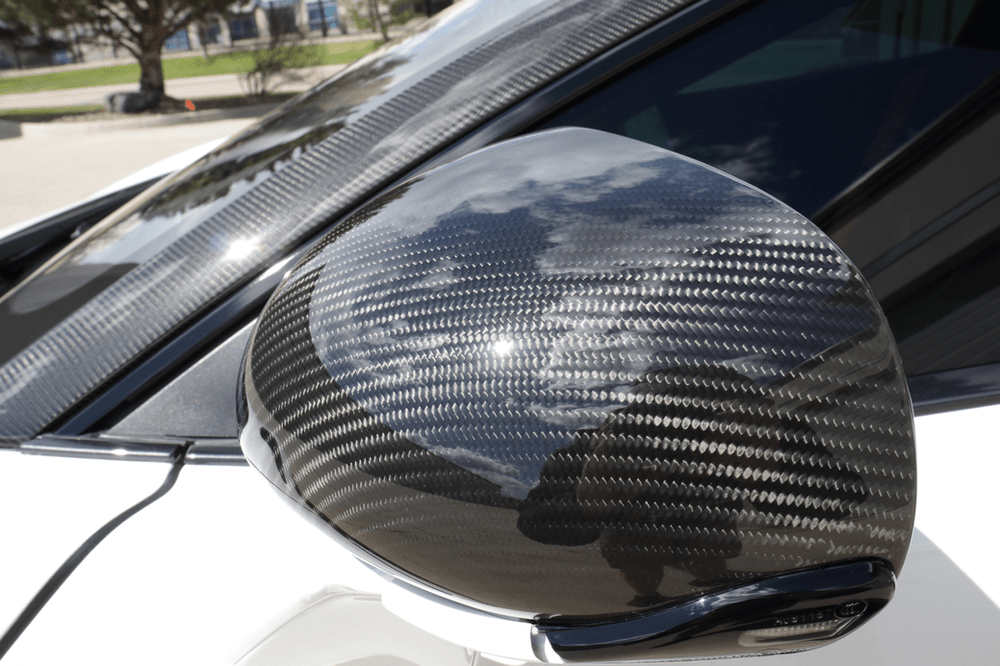 A close up of a carbon fiber side mirror on a car