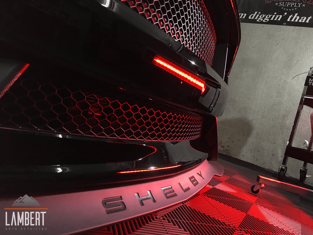 A black shelby gt500 is parked in a garage.