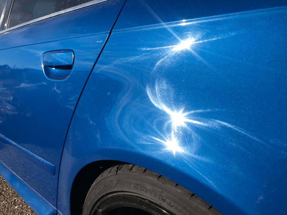 A close up of a blue car with the sun shining on it