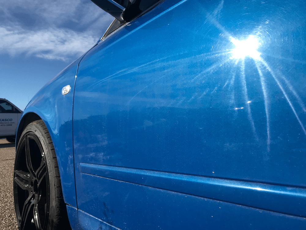 A close up of a blue car with the sun shining on it