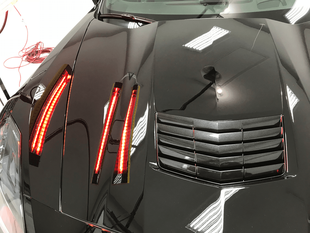A black car with red lights on the hood