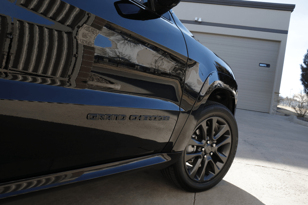 A blue car is parked in front of a garage.