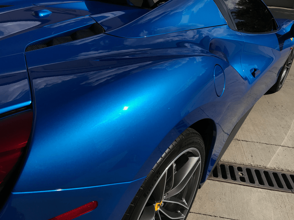 A blue sports car is parked next to a drain