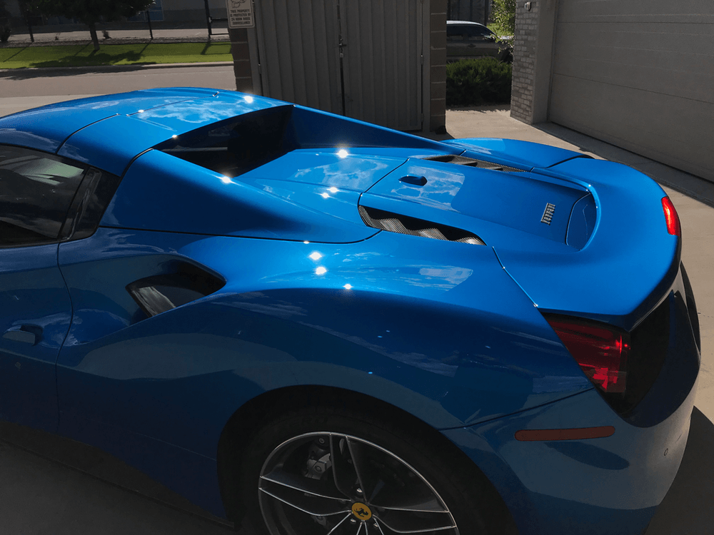 A blue sports car is parked in front of a garage door