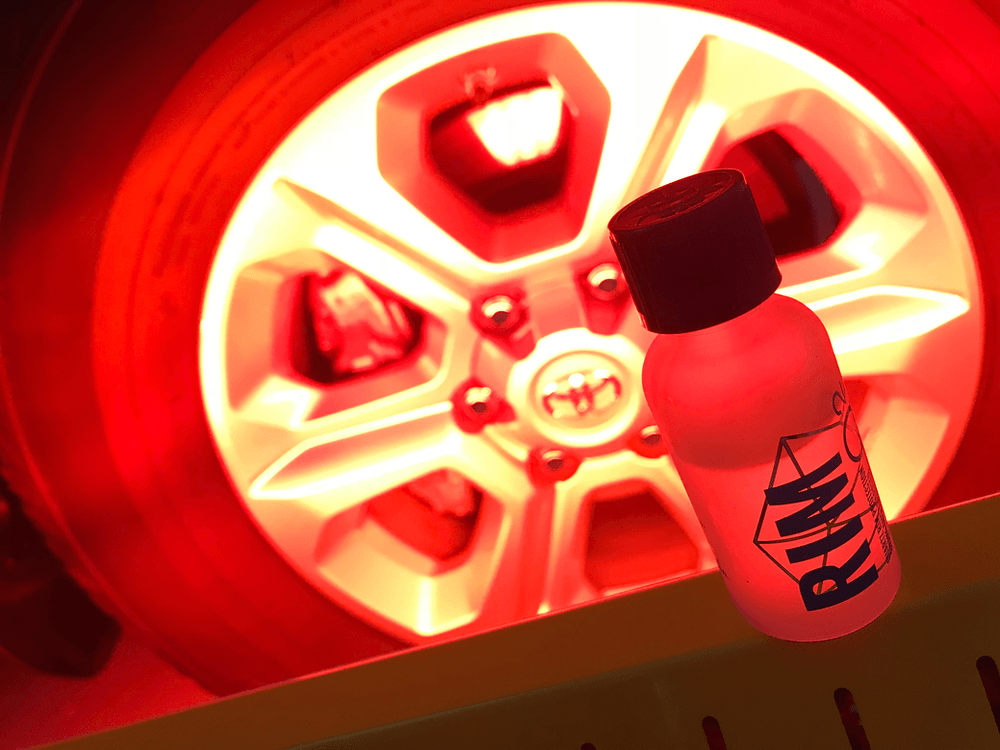A bottle of rim sitting next to a car wheel
