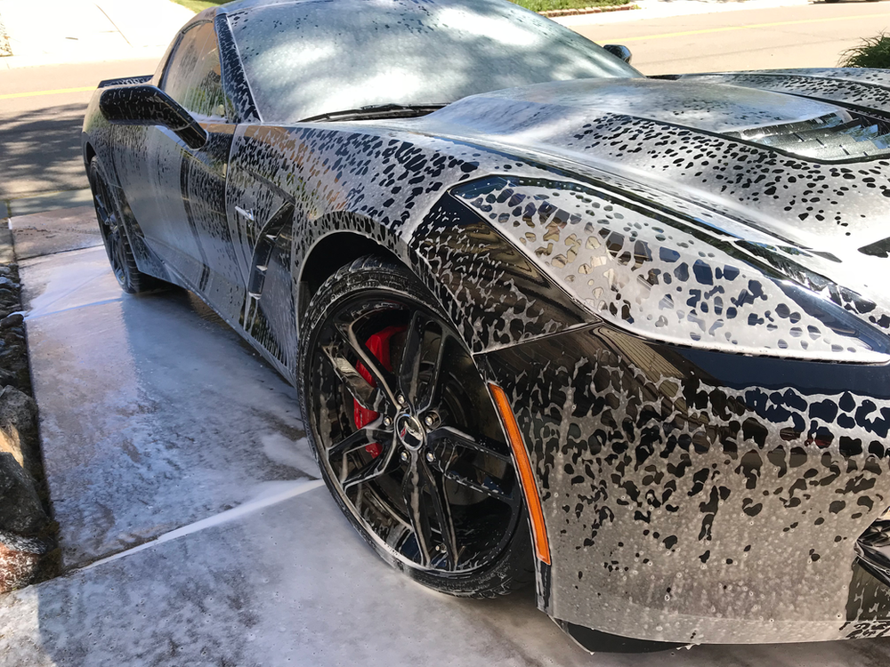 A black sports car is sitting on a concrete surface covered in foam.