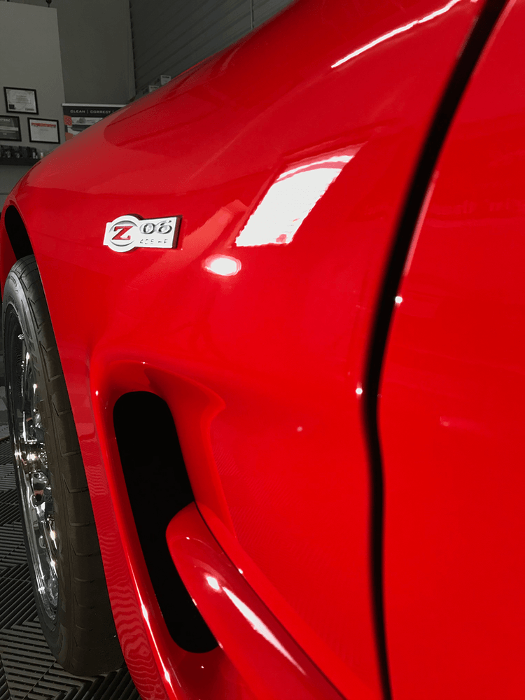 A red car has a sticker on the side that says zoo