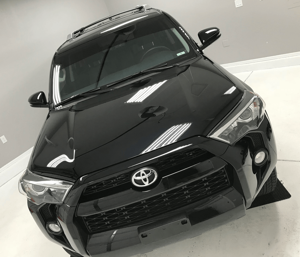 A black toyota 4runner is parked in a garage.
