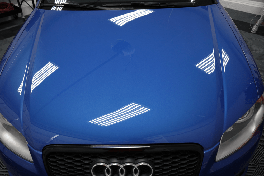 A close up of the hood of a blue car.