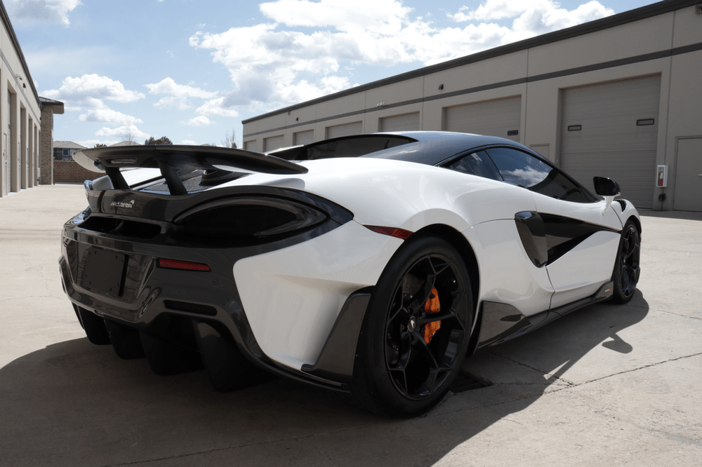 A white sports car is parked in front of a building.