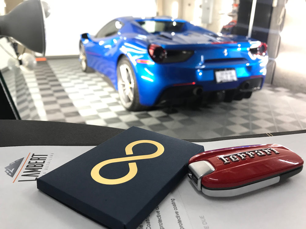 A blue car is parked in a garage next to a ferrari key