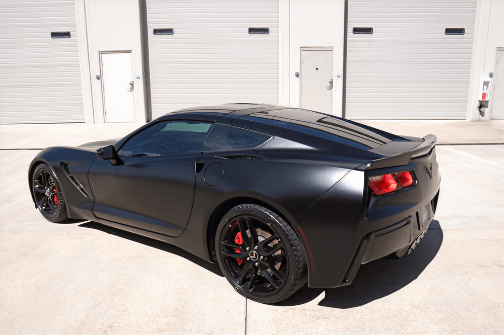 A black sports car is parked in front of a building.