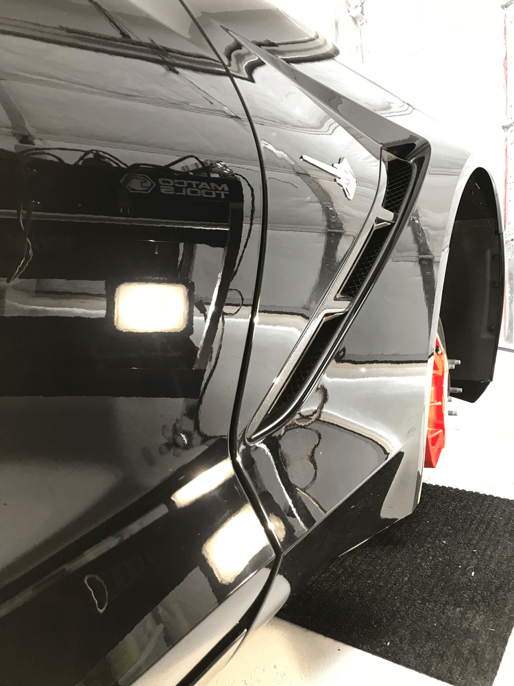 A black car is parked in a garage with the door open