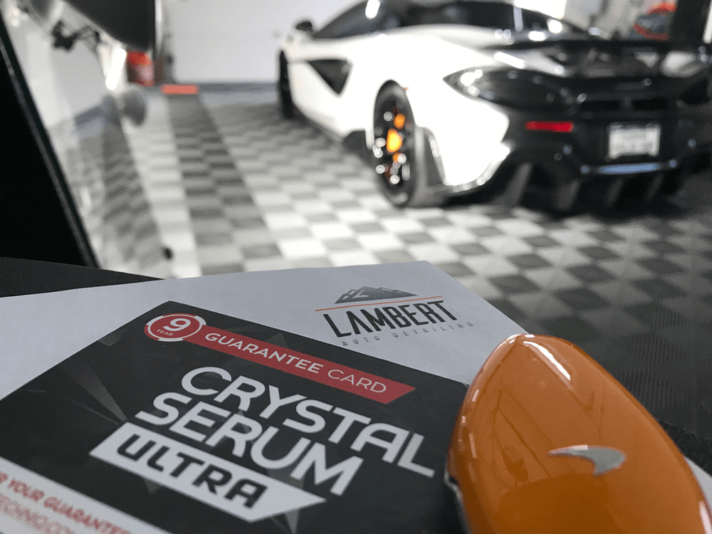A car is parked in a garage next to a crystal serum ultra guarantee card