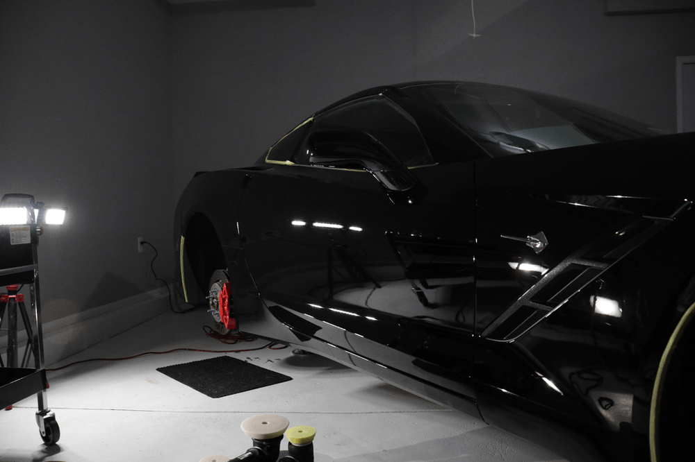 A black sports car is being polished in a garage.