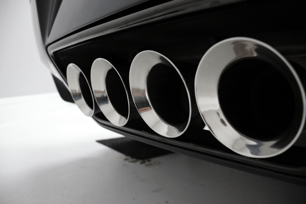 A close up of a car 's exhaust pipes on a white surface.