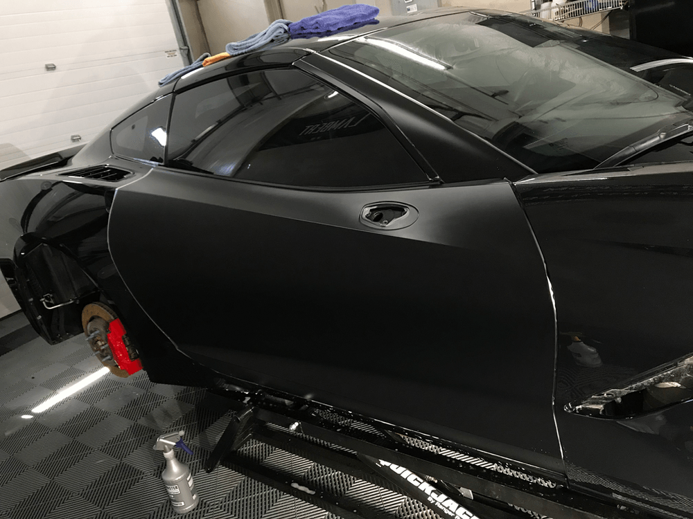 A black sports car is parked in a garage.