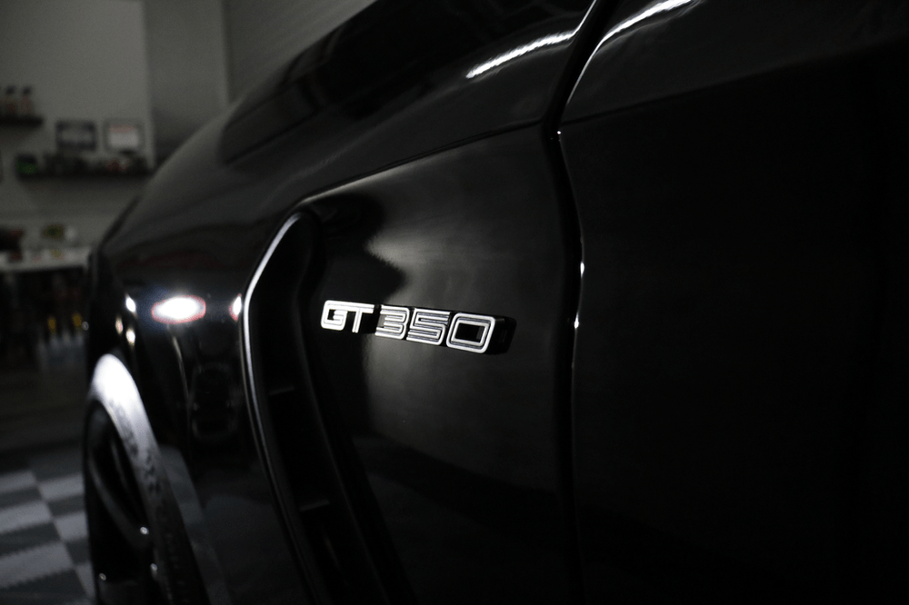 A black gt350 mustang is parked in a garage