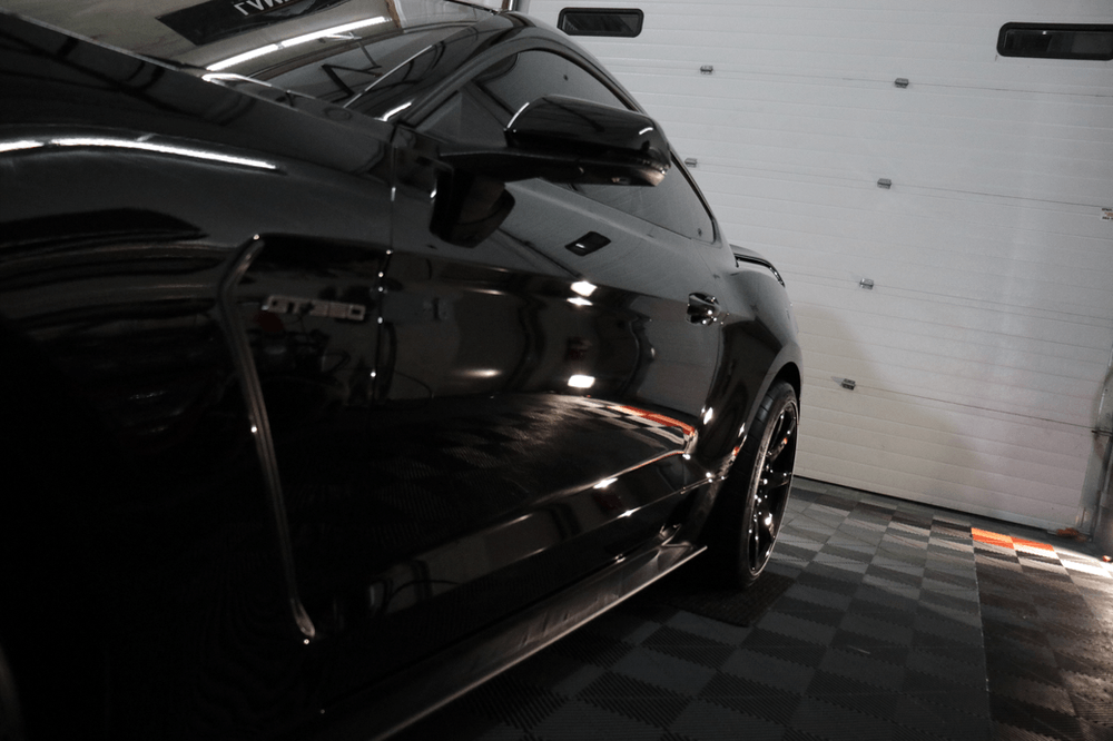 A black car is parked in front of a garage door.