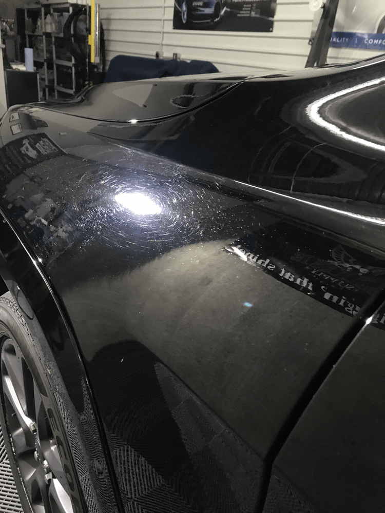 A black car is parked in a garage.