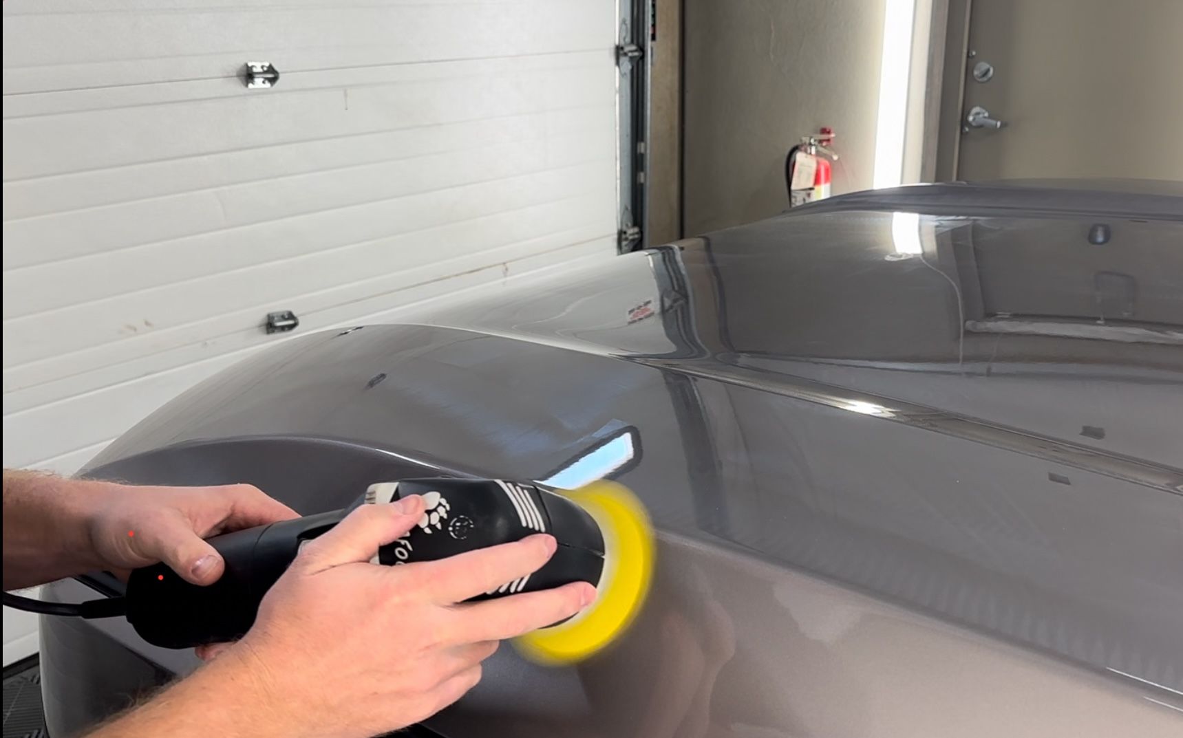 A person is polishing a car with a machine.