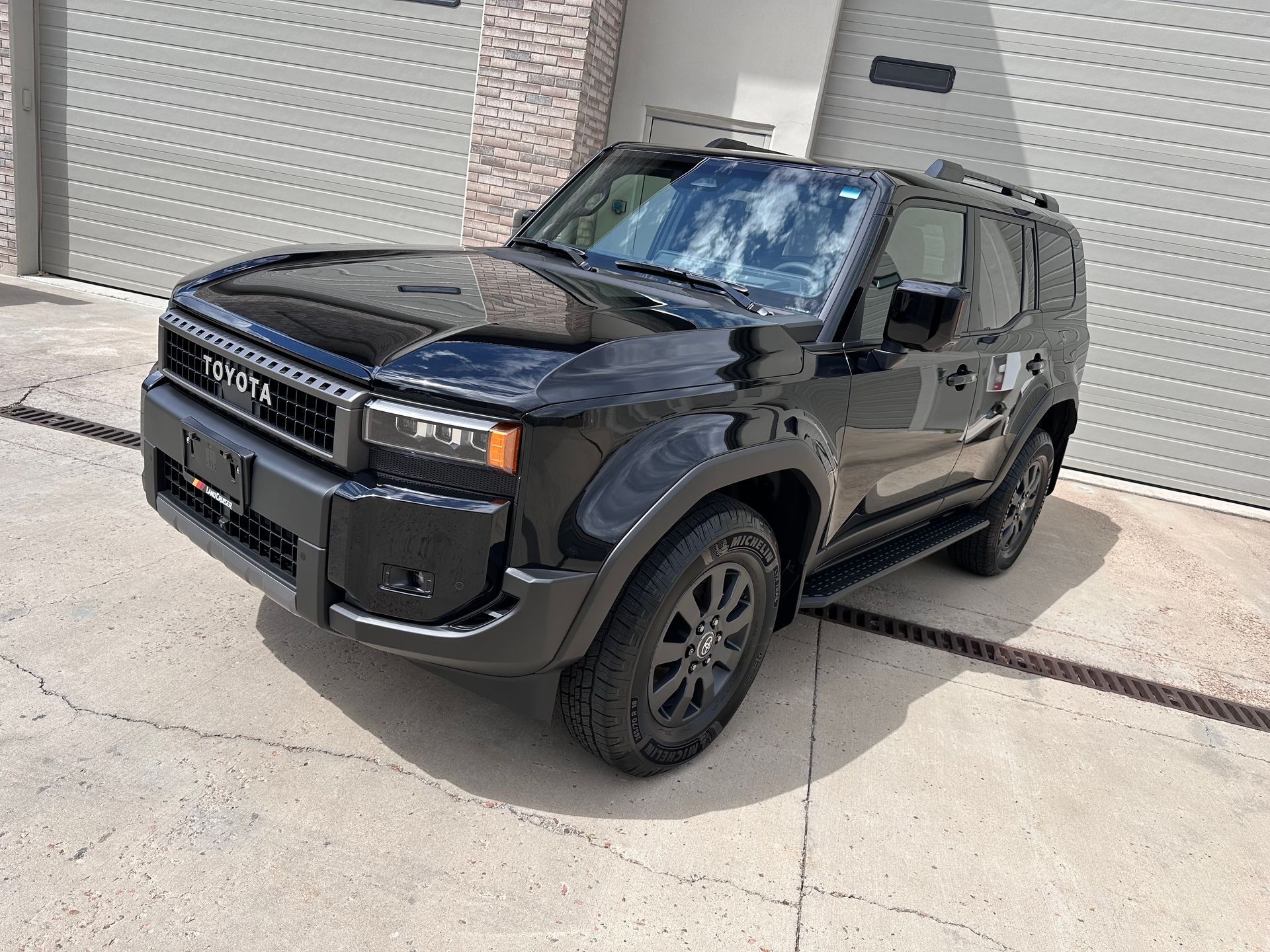 A black toyota land cruiser is parked in front of a garage door.