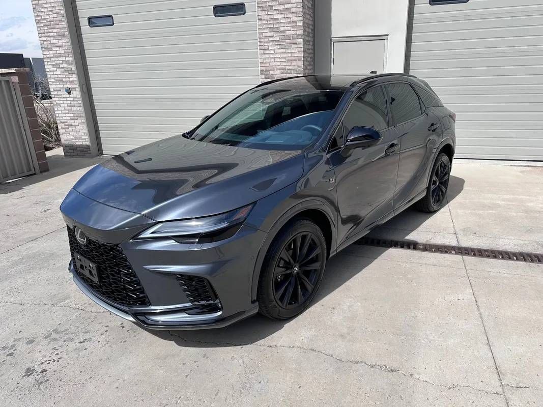 A gray lexus nx is parked in front of a garage.