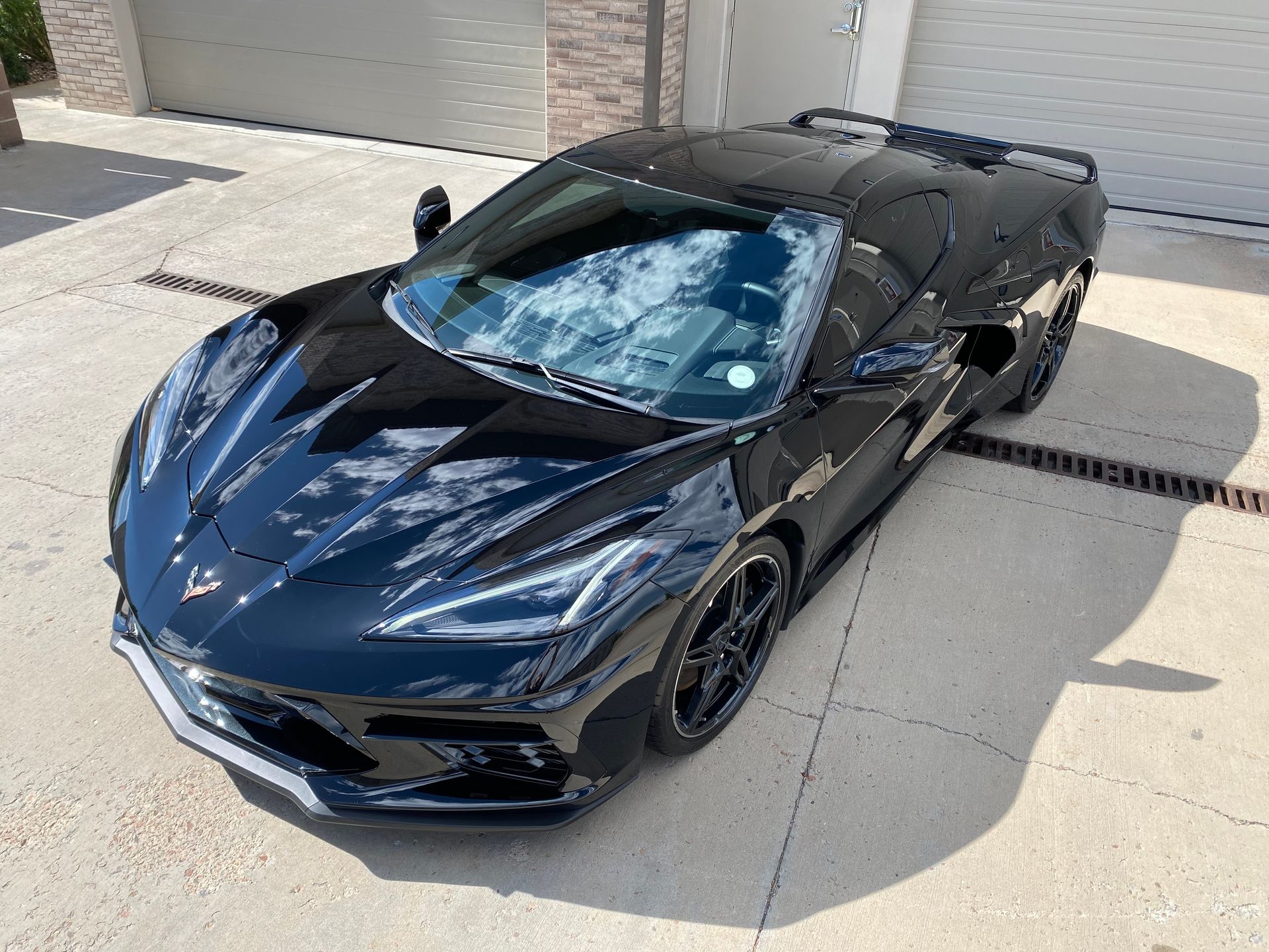 A black sports car is parked in a driveway next to a garage.