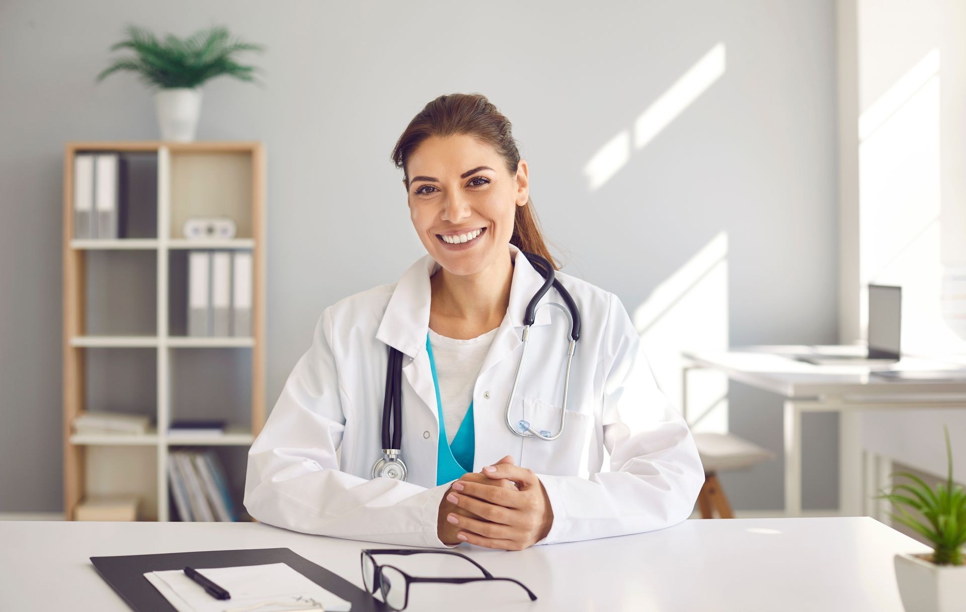 Healthcare professional with stethoscope seated at a desk in a bright office. Healthcare professional with stethoscope seated at a desk in a bright office.