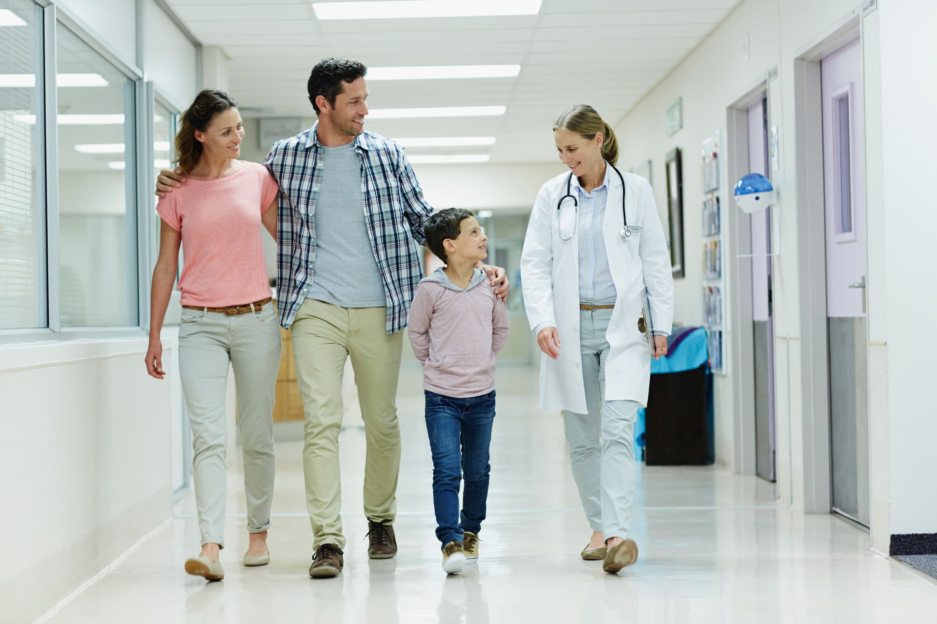 A doctor is walking with a family in a hospital corridor. A doctor is walking with a family in a hospital corridor.