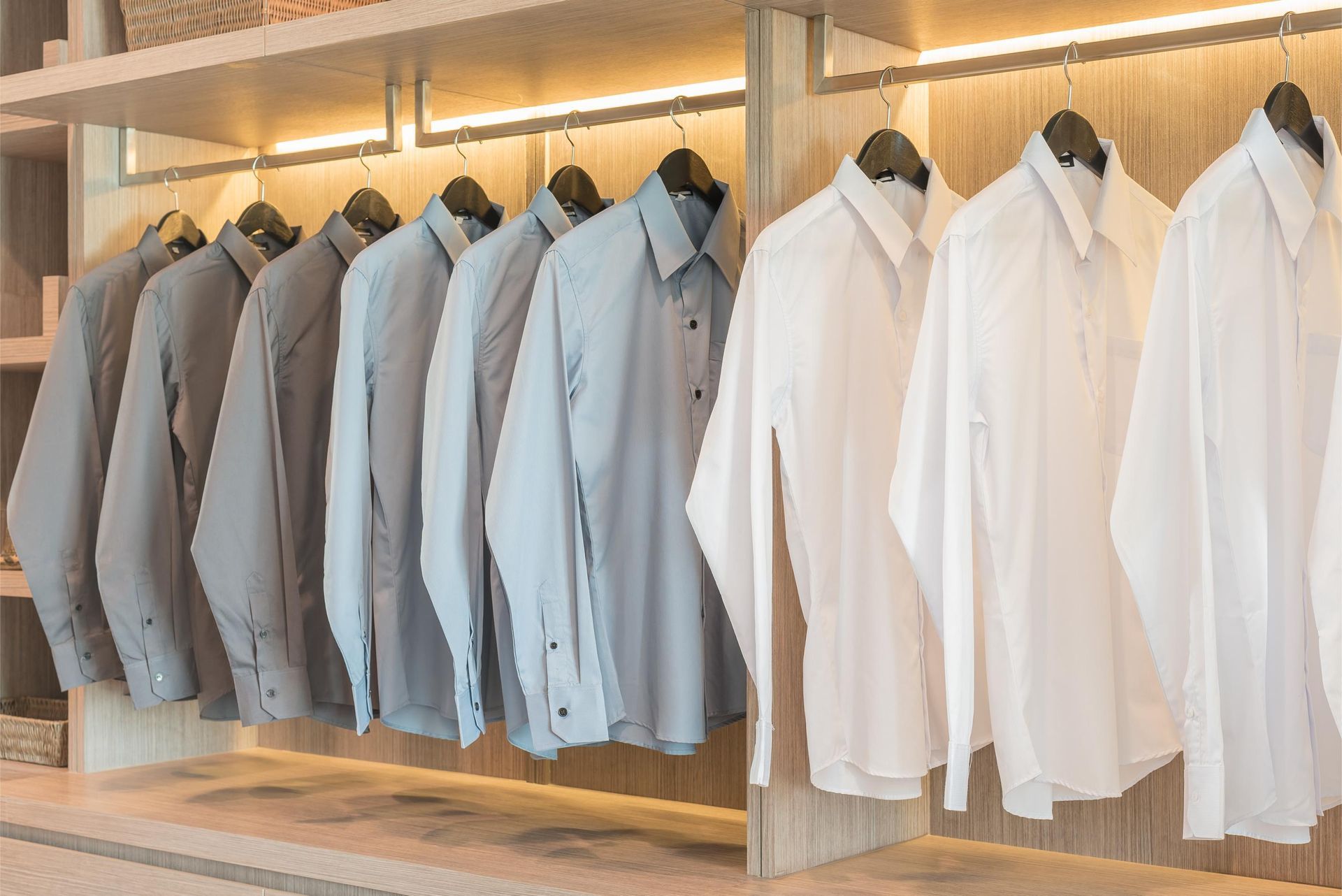 a row of shirts hanging on a rack in a closet