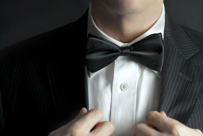 a man in a suit and bow tie is adjusting his jacket