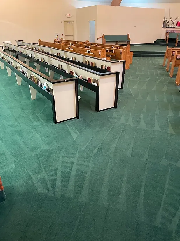 Empty church pews with green carpet and wooden seating in a sanctuary