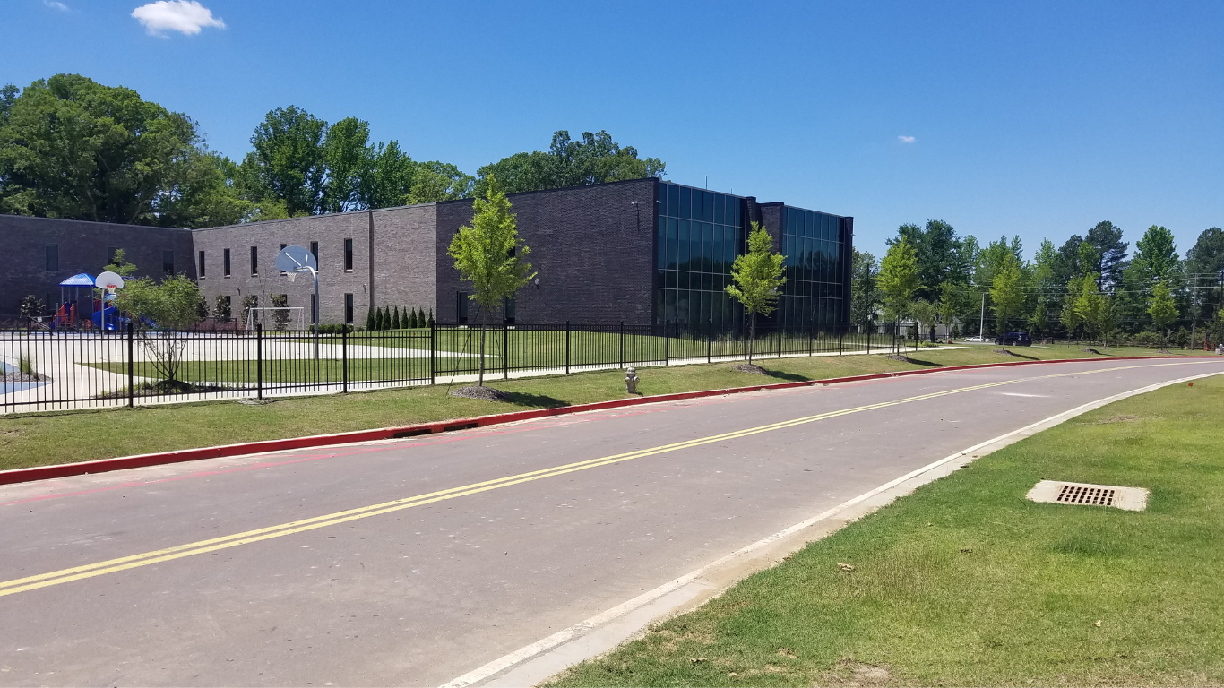 School building with black metal fence and road in front.